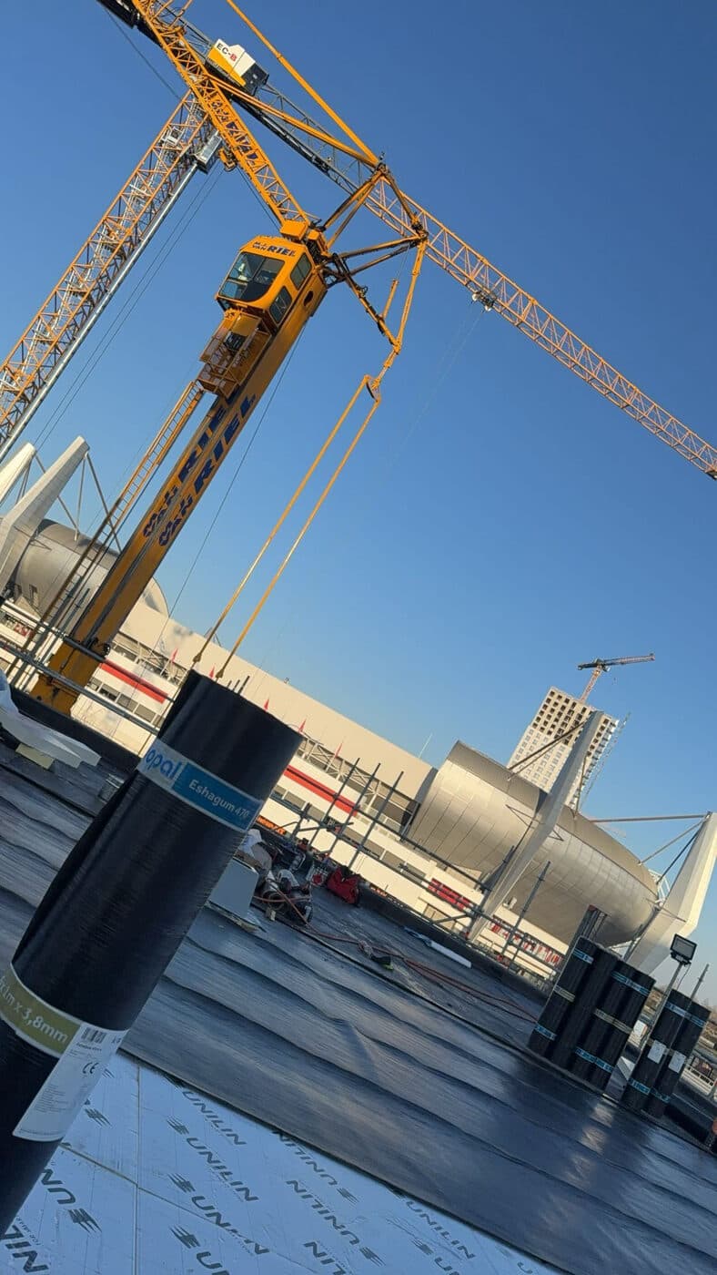 Bitumen dakbedekking op een groot utiliteitsbouwproject met bouwkraan