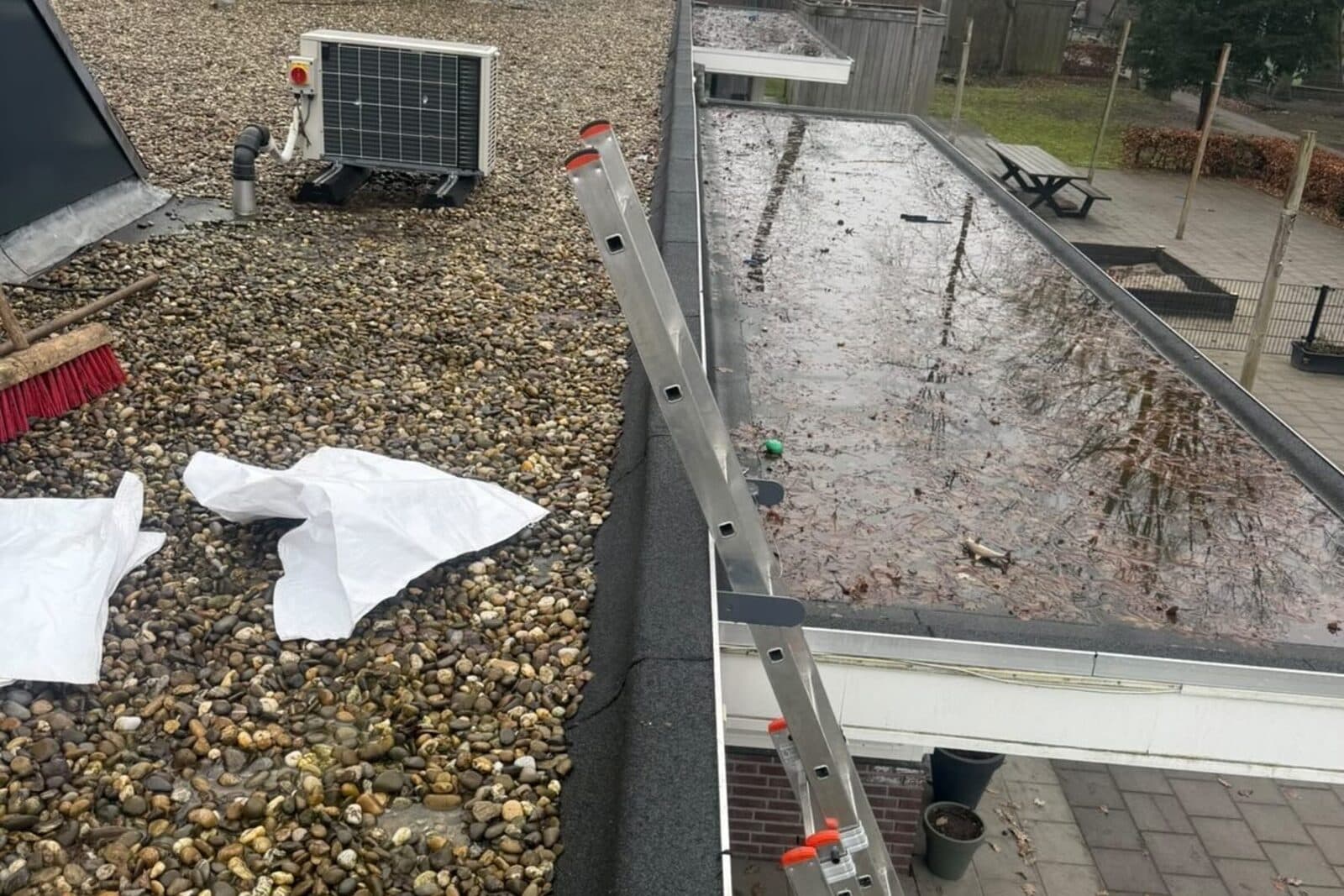 Zinken dakgoot langs een plat dak met grindafwerking