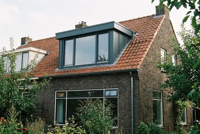 Dakkapel met donkere bekleding op het achterdakvlak van een woning met pannendak