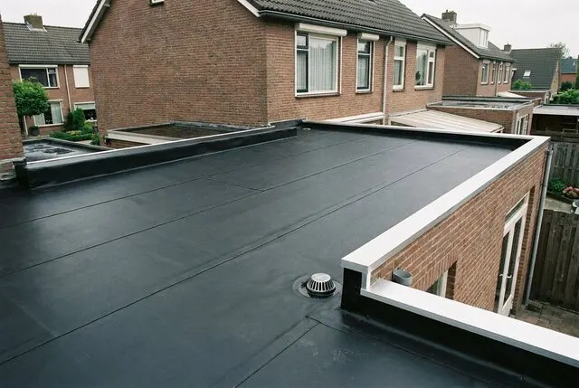 Plat dak van een uitbouw met zwarte EPDM-dakbedekking en een dakrand van aluminium