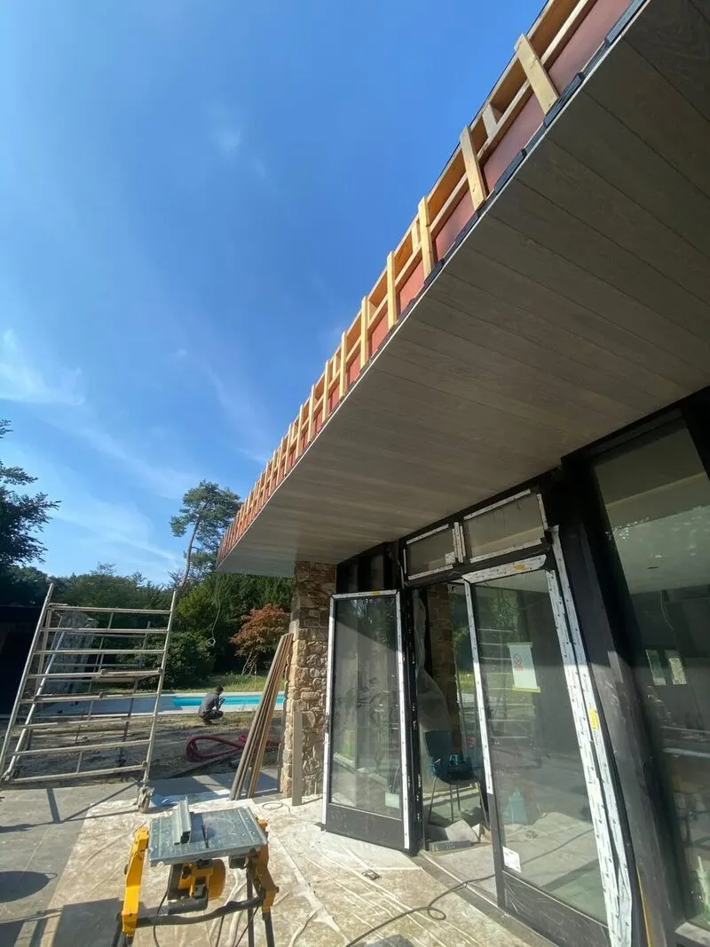 Moderne dakrand met overstek langs een glazen gevel